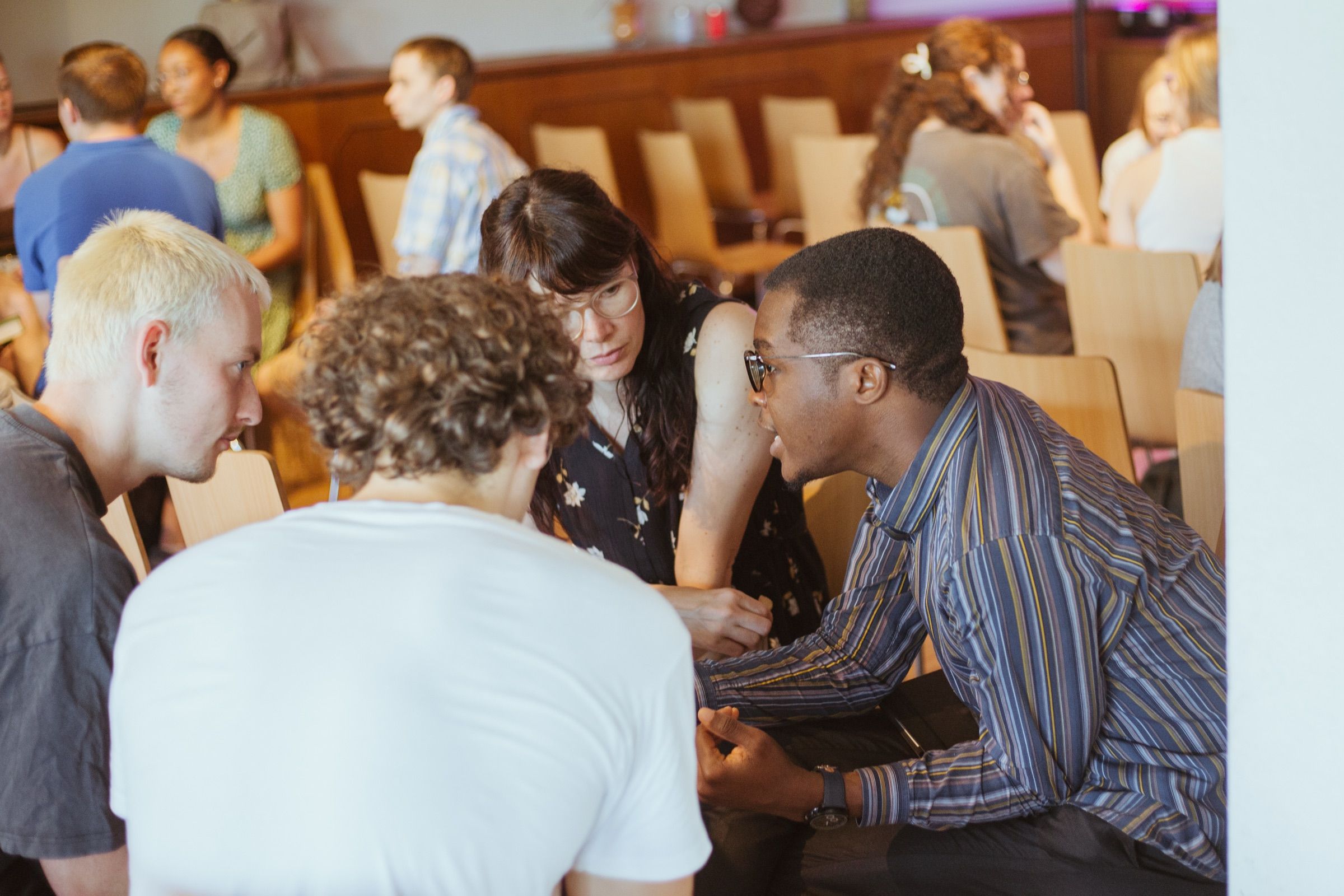 Four young people sitting close together, deep in conversation