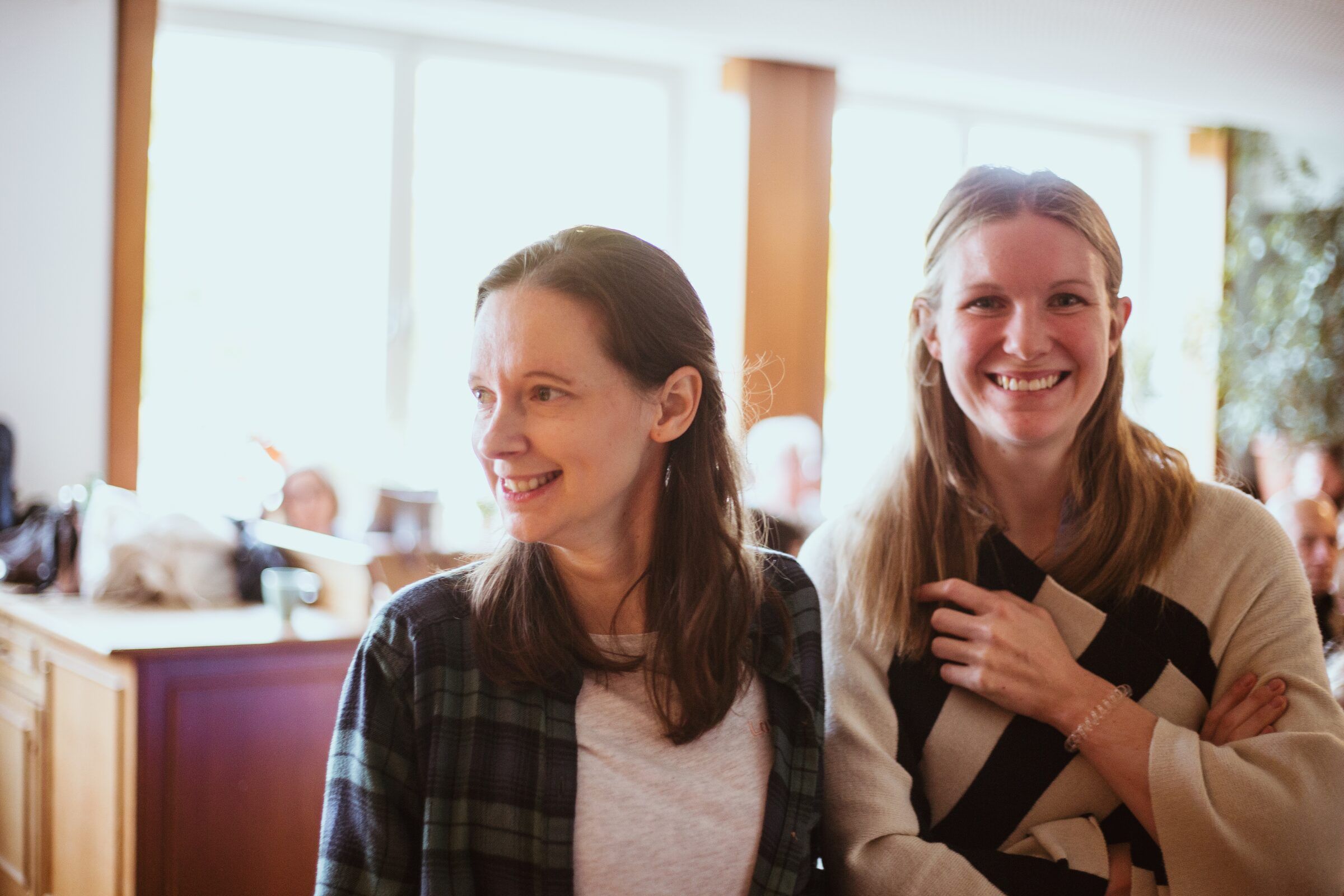 Zwei Frauen lachen gemeinsam im Gemeinderaum