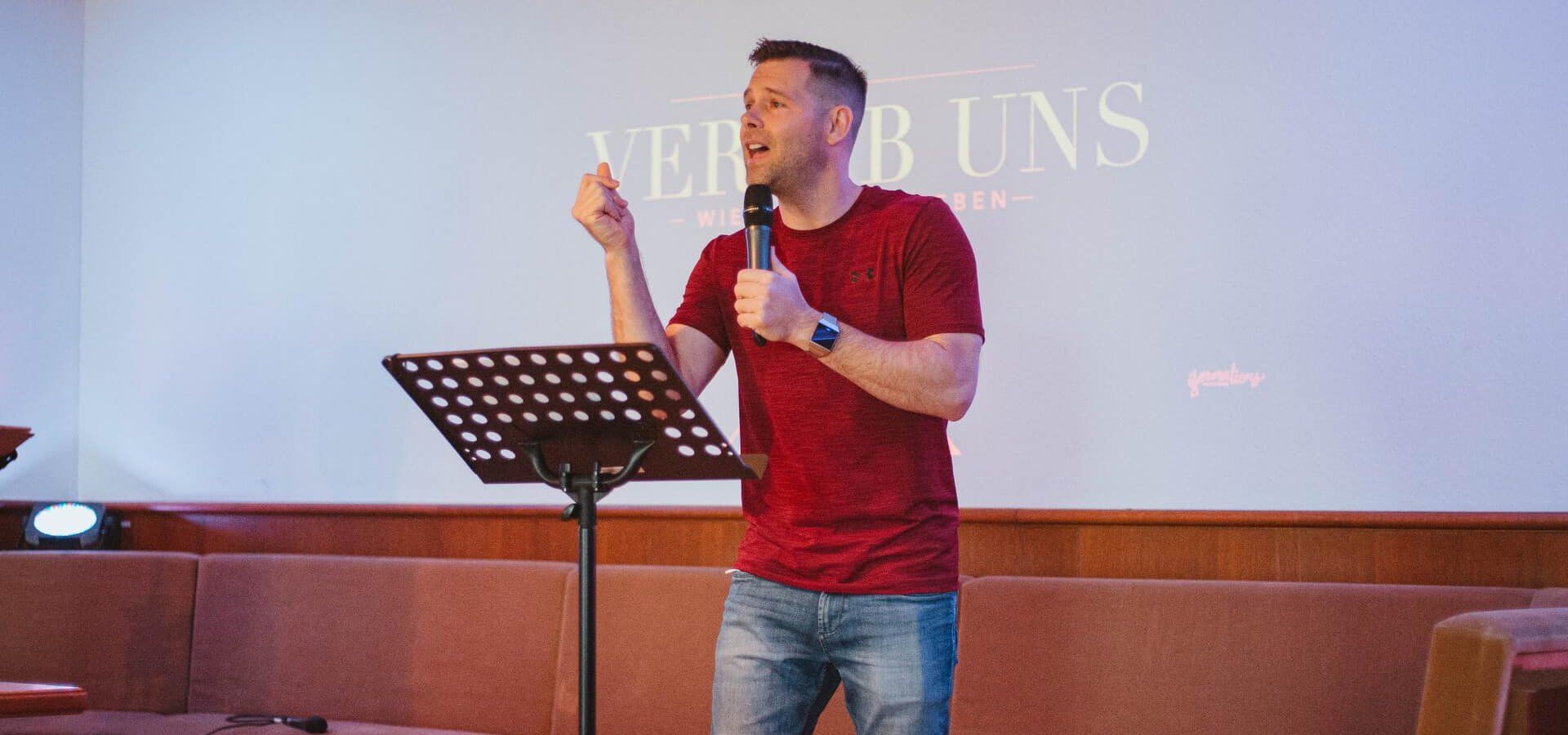 Ein Pastor predigt vor der Leinwand